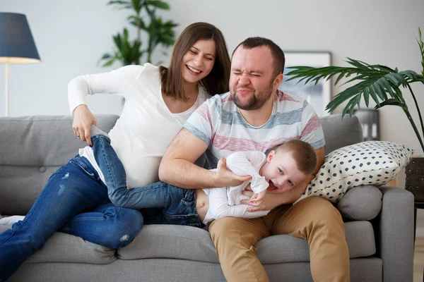 Foto de mujer embarazada feliz, hombre con hijo en sofá gris —  Fotos de Stock