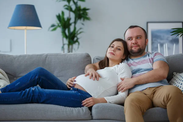 Bild von schwangerer Frau und Mann auf grauem Sofa — Stockfoto