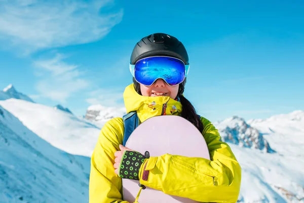 Foto de mujer deportiva con casco y snowboard sobre el fondo de las colinas nevadas — Foto de Stock