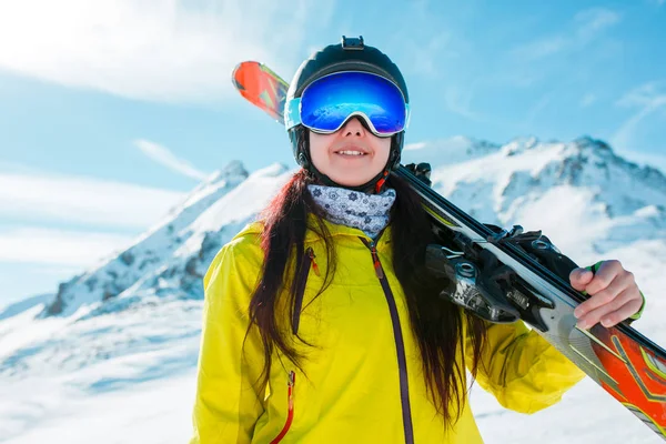 Bild eines Mädchens mit Helm, Maske mit Skiern auf der Schulter — Stockfoto