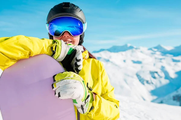 Retrato de menina sorridente no capacete e máscara com snowboard no fundo de colinas nevadas — Fotografia de Stock