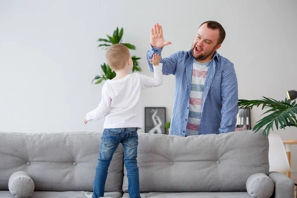 Familienfoto des kleinen Sohnes auf dem Sofa beim Händedruck mit Papa — Stockfoto