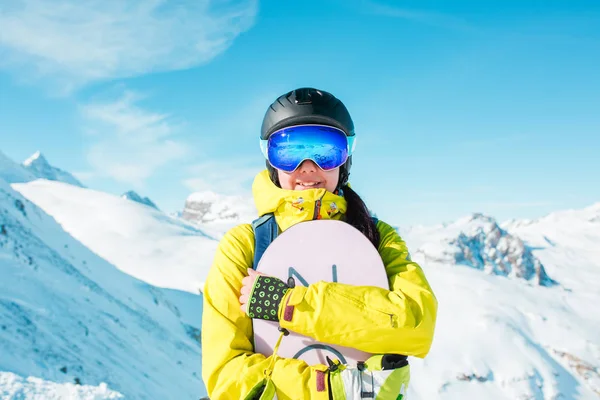 Imagen de una mujer deportiva con casco y snowboard sobre el fondo de colinas nevadas —  Fotos de Stock