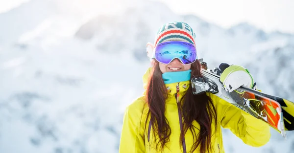 Obraz žena s lyžema na rameni v pozadí zasněženého kopce — Stock fotografie
