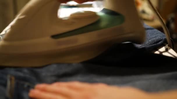 Женщина гладит джинсы утюгом — стоковое видео