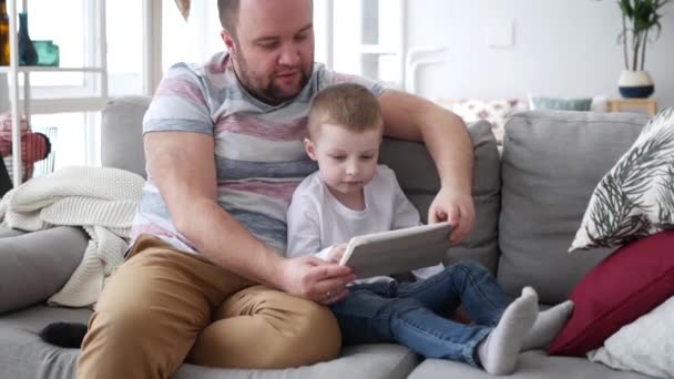 Daddy and son websurfing on digital tablet at home — Stock Video