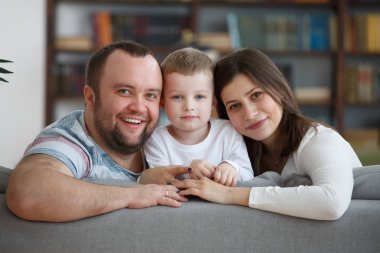 Gri koltukta oturan oğlu ile aile gülümseyen resim