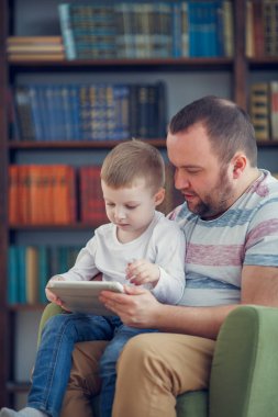 Baba ve küçük oğlu ile tablet yeşil sandalye üzerinde oturan aile görüntüsü