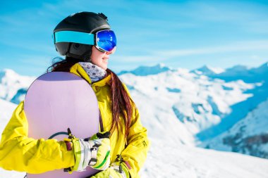 Kask ve maske ile snowboard karlı tepelerin arka plan üzerinde gülümseyen kadın resim