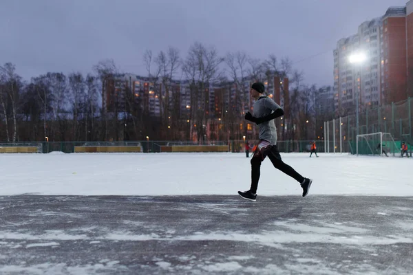 Foto des Athleten in schwarzer Sportkleidung beim Laufen im Winterpark — Stockfoto