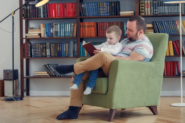 父亲看书给儿子坐在椅子上的照片 — 图库照片