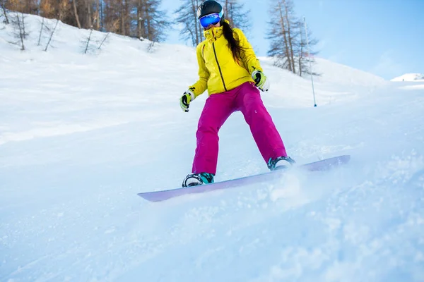 Picture of athletic woman wearing helmet and mask snowboarding from snowy slope with trees — Stock Photo, Image