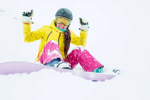 Foto van sportieve lachende vrouw in helm en masker met haar armen verhoogd met snowboard — Stockfoto