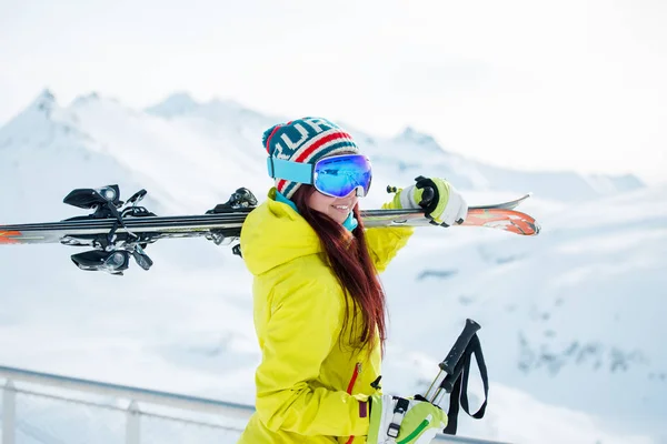 Foto de mujer deportiva sonriente con esquís en el hombro contra — Foto de Stock