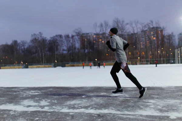 Foto eines Mannes in schwarzer Sportkleidung beim Laufen im Winterpark — Stockfoto