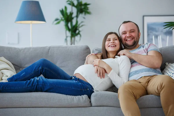 Image of happy pregnant woman and man on gray sofa — Stock Photo, Image