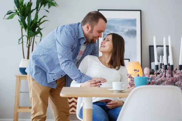 Зображення щасливого чоловіка обіймає вагітна дружина сидить за столом зі свічками — стокове фото