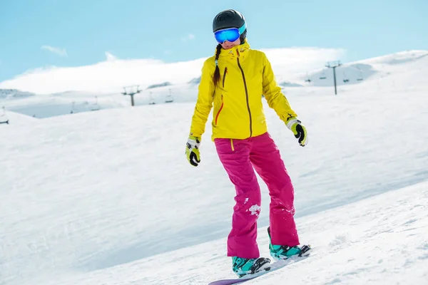 Picture of young athlete girl wearing helmet in sports clothes snowboarding