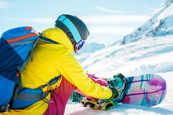 Imagem de mulher de esportes no capacete sentado na neve com snowboard — Fotografia de Stock