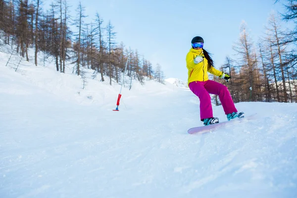 Foto de atleta femenina con casco y máscara de snowboard desde la ladera nevada con árboles —  Fotos de Stock