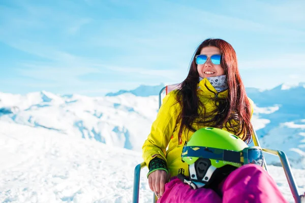 Zdjęcia sportowe długowłosa brunetka z kasku na krzesło w ośrodku narciarskim — Zdjęcie stockowe