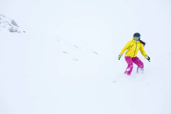 Imagen de atleta femenina que usa casco con el desarrollo de snowboard de pelo desde la ladera de la montaña —  Fotos de Stock