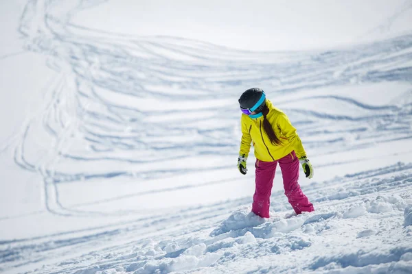 Foto de morena con casco y máscara en ropa deportiva snowboard desde la ladera nevada de la montaña —  Fotos de Stock