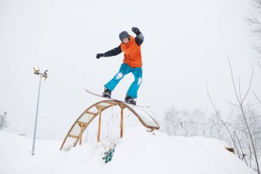 Fotoğraf arka plan ağaç karşı sıçrama tahtası ile snowboard üzerinde paten sporcunun