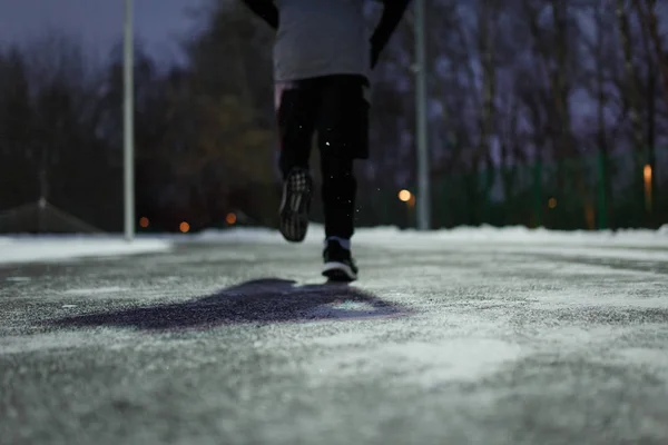 男子穿着运动鞋在房屋背景下在冬季公园跑步的照片 — 图库照片