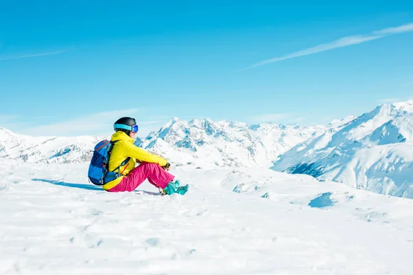 Foto di donna sportiva che indossa casco e maschera siede sul pendio innevato — Foto Stock