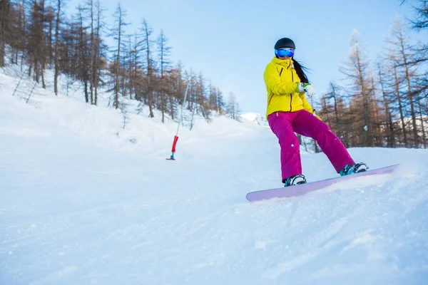 Kask ve ağaçları ile karlı yamaç üzerinden snowboard maskesi giyen kadın atlet görüntüsünü — Stok fotoğraf