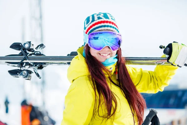 Portret uśmiechający się sportowe kobieta z nartami na jej ramieniu — Zdjęcie stockowe