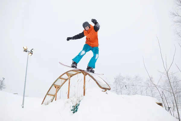 Foto de atleta patinando sobre tabla de snowboard con trampolín sobre fondo de árboles — Foto de Stock