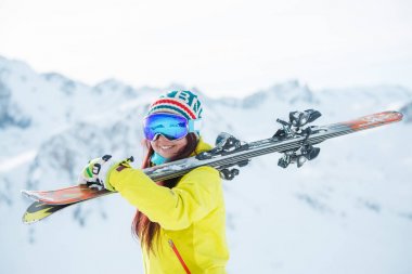 Yana doğru ayakta omzuna kayaklar ile maskeli kadın resim