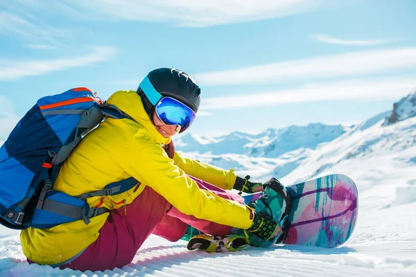 Imagen de mujer deportiva en casco sentado en la nieve con snowboard —  Fotos de Stock