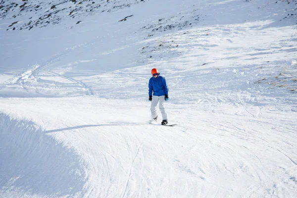 Foto do homem no capacete montando snowboard de encosta nevada — Fotografia de Stock