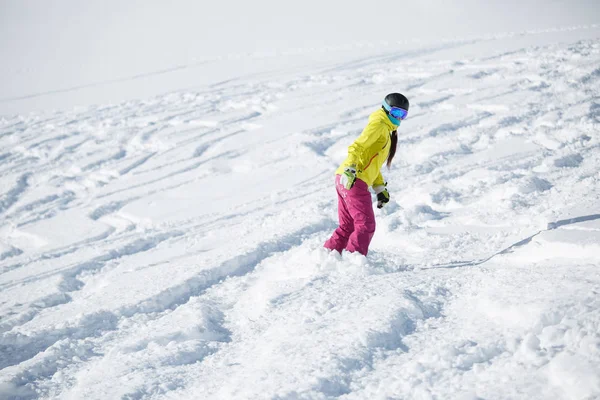 Foto de atleta niña en casco y máscara, snowboard desde la ladera nevada de la montaña — Foto de Stock