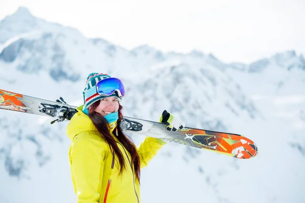 Obrázek sportovní ženy s lyžema na rameni v pozadí zasněženého kopce — Stock fotografie