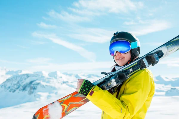 Photo de femme sportive en casque avec des skis sur son épaule sur fond de collines d'hiver — Photo