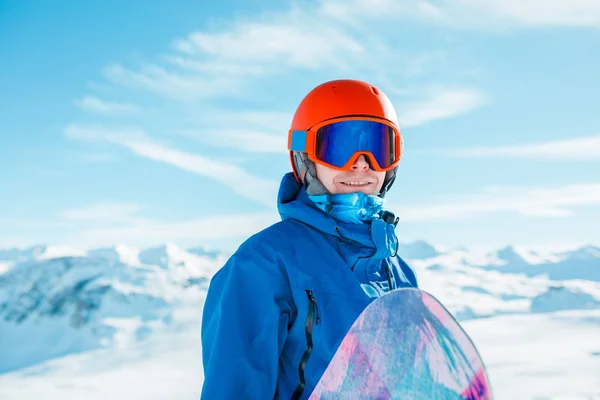 Bild des Sportlers mit Helm und Snowboard auf dem Hintergrund des schneebedeckten Hügels — Stockfoto