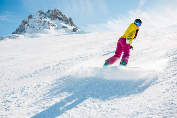 Foto de una mujer deportista haciendo snowboard en la ladera nevada — Foto de Stock