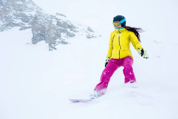 Zdjęcie z sportowiec dziewczynka w hełm z rozwijającymi się włosów, snowboarding od stoku góry — Zdjęcie stockowe