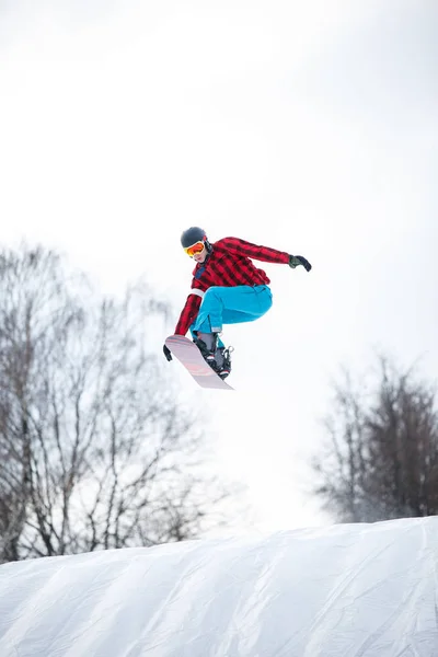 Foto de atleta en casco montando snowboard desde la pendiente de la nieve —  Fotos de Stock