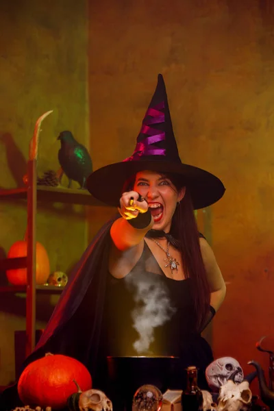 Фото ведьмы в черной шляпе с протянутой рукой с волшебной палочкой — стоковое фото