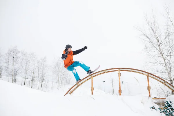 Картина молодого спортсмена катається на лижах на сноуборді з трампліном на фоні дерев — стокове фото