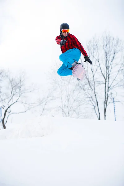 Imagem de homem desportivo com snowboard jumping em resort nevado — Fotografia de Stock