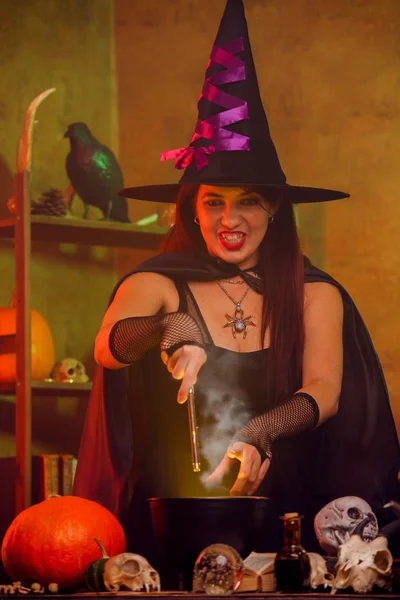 Retrato de bruxa em chapéu preto com varinha mágica e caldeirão — Fotografia de Stock