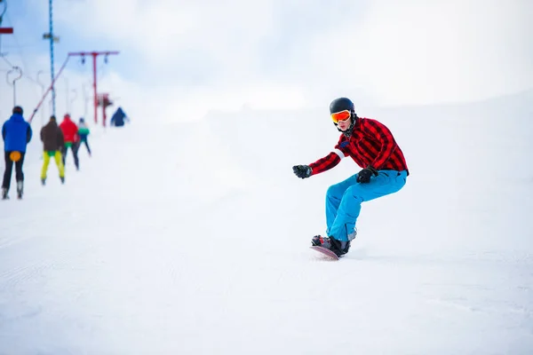 Foto do atleta com snowboard pulando na colina nevada — Fotografia de Stock