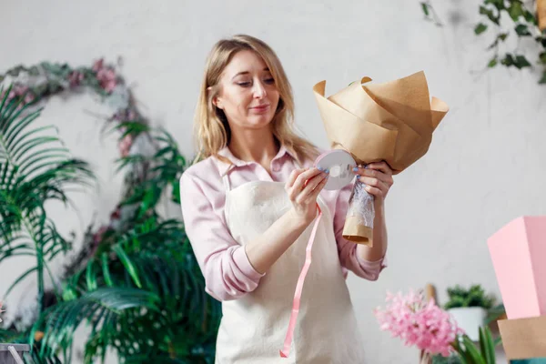 Image of blonde florist in apron with bouquet in flower shop — Stock Photo, Image