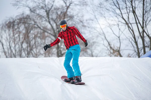 Imagen del hombre usando casco montando snowboard desde la pendiente de la nieve — Foto de Stock